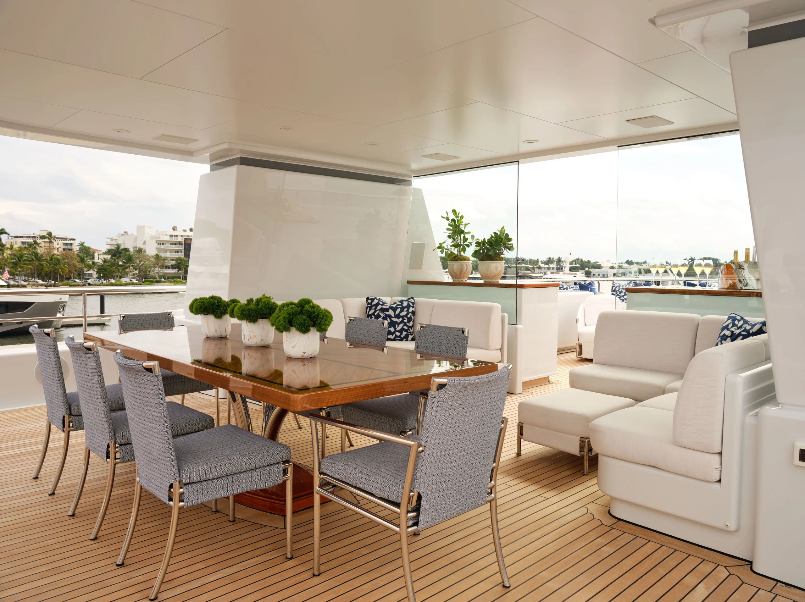 Luxury yacht interior design featuring an outdoor dining and lounge area with teak decking, upholstered seating, and open-air layout
